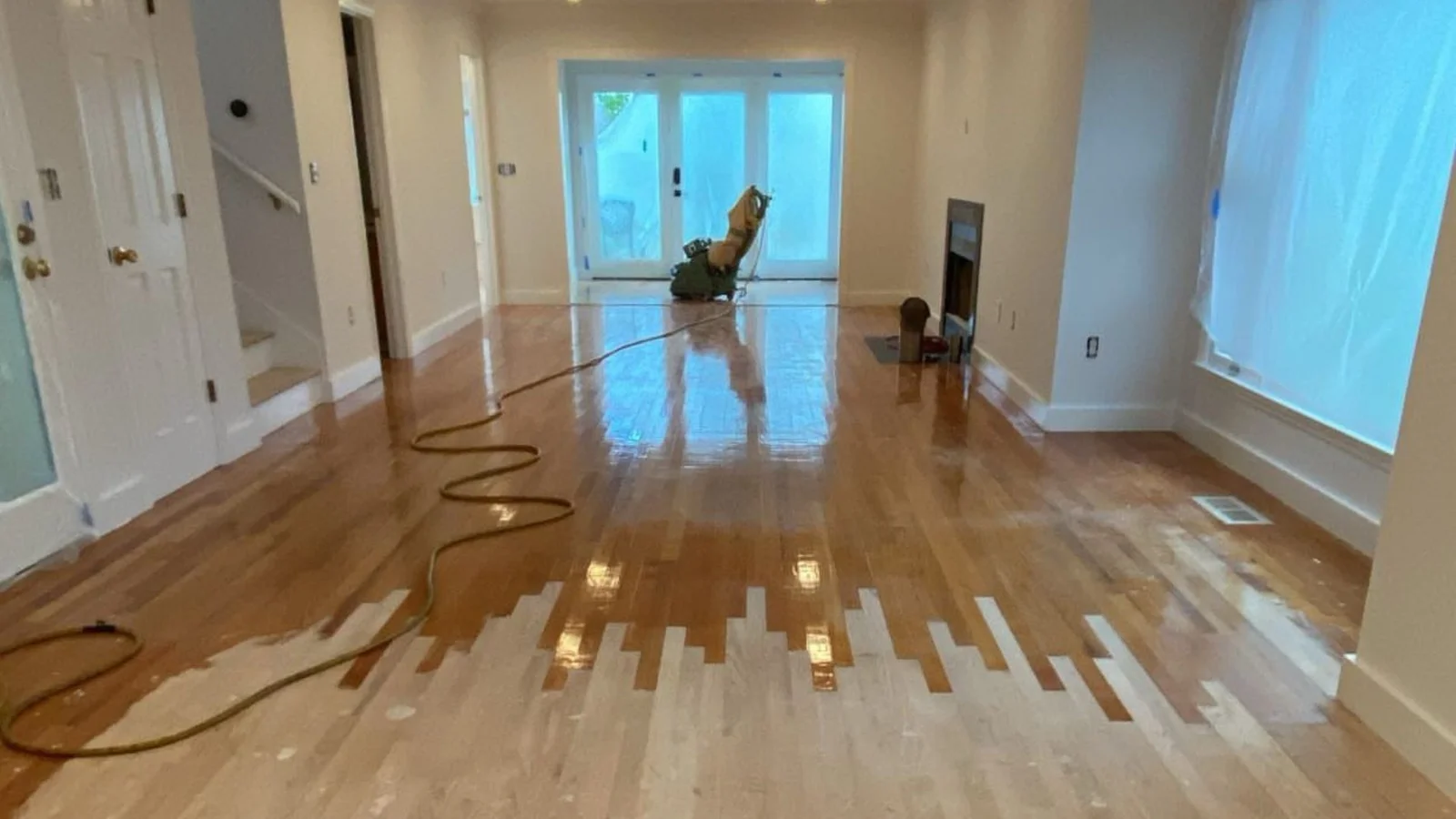 Hardwood floor repair with patched sections and fresh finish in open room