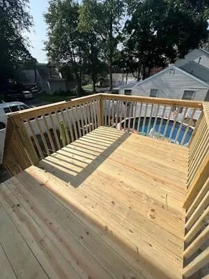 Newly constructed pressure-treated wood deck with railings and solid decking boards