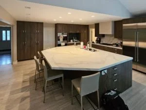 Hardwood flooring installation in modern kitchen with island and stainless steel appliances
