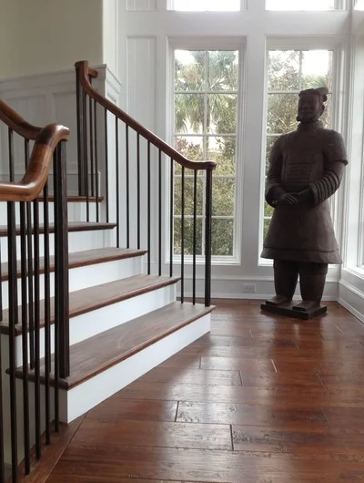 Medium-tone hardwood flooring with white stair risers and wood stair treads, metal railing, transom windows