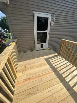 Newly installed pressure-treated wood deck with railings and exterior door access