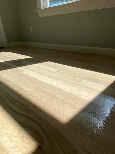 Light oak hardwood flooring with matte finish in residential room with green walls