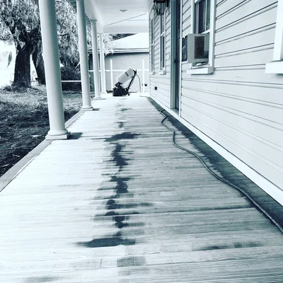 Hardwood flooring installed on covered porch with support columns and natural wood grain finish