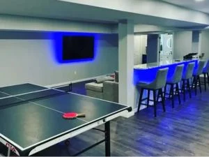 Dark hardwood flooring in recreation room with ping pong table and bar seating