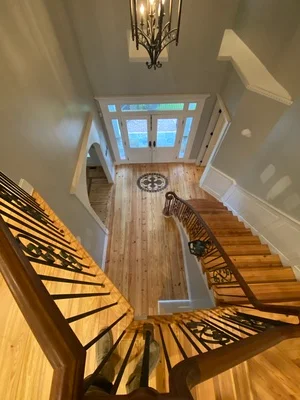 Solid hardwood flooring installation with matching wood staircase and natural light from skylight