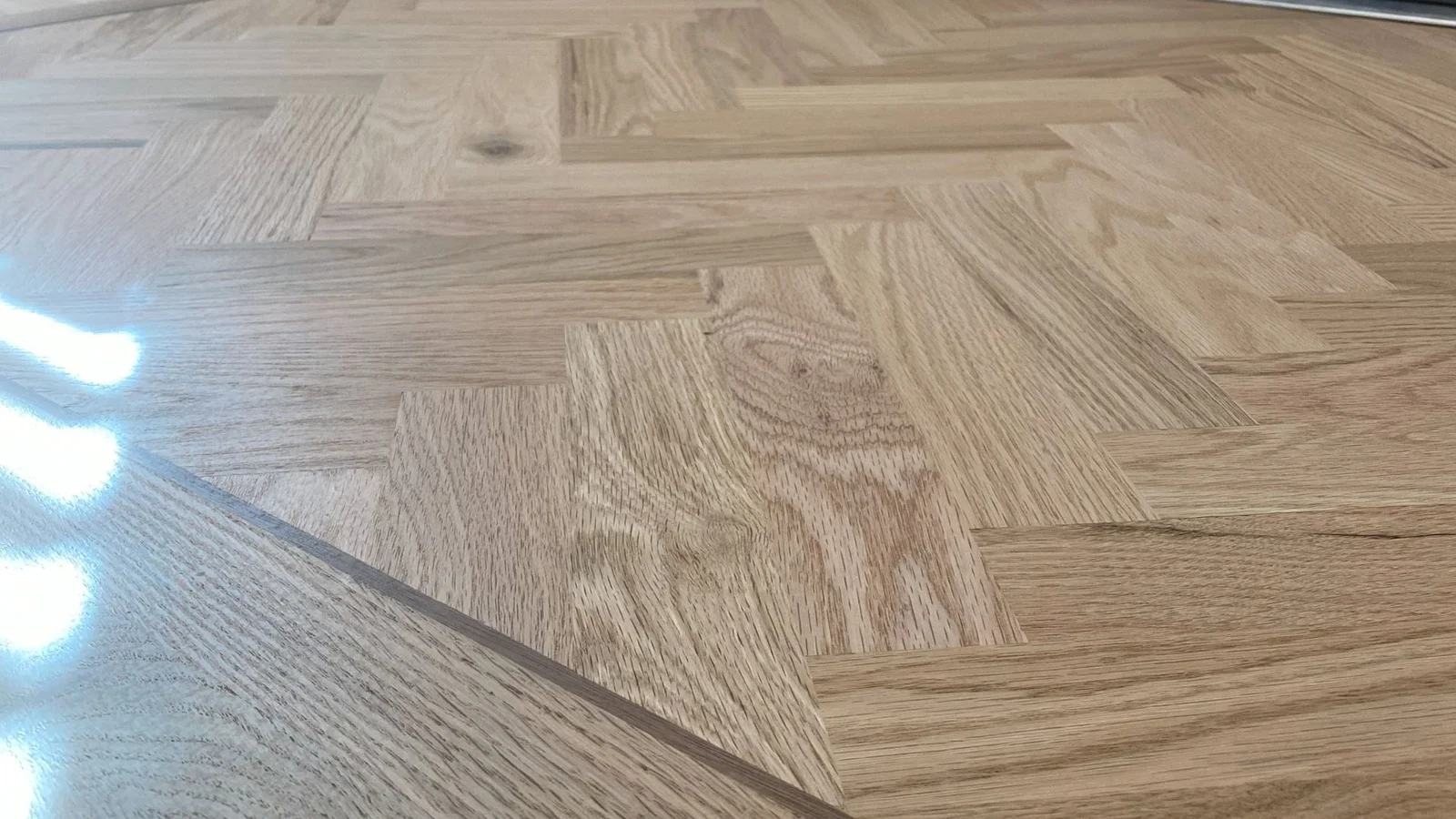 Light oak parquet flooring in herringbone pattern with geometric wood grain detail