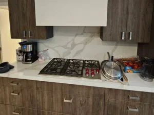 Dark wood cabinetry with marble countertop, gas cooktop, and stainless steel hardware