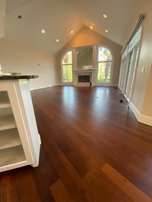 Newly installed hardwood flooring in vaulted room with arched ceiling and fireplace