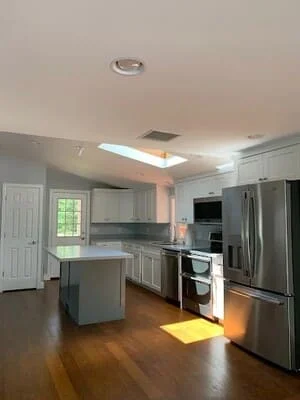 Medium-tone hardwood flooring installed in kitchen with island and stainless steel appliances