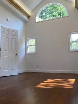 Dark hardwood flooring installed in room with white trim and arched window