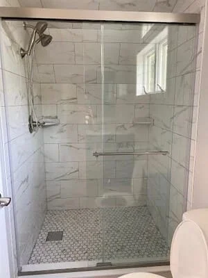 Marble subway tile shower with hexagonal floor mosaic and frameless glass enclosure