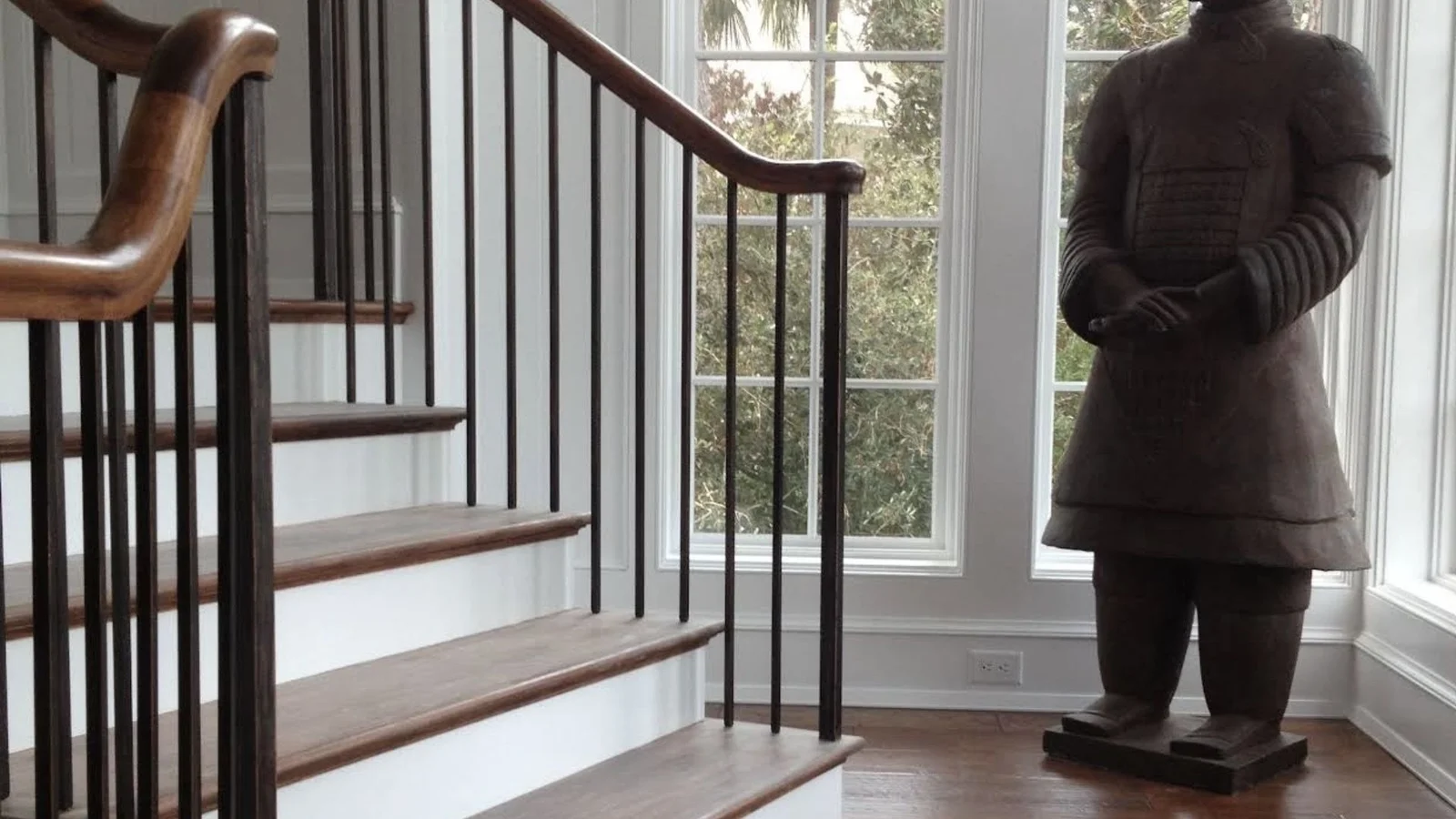 Hardwood staircase with wood treads, curved handrail, and black metal spindles