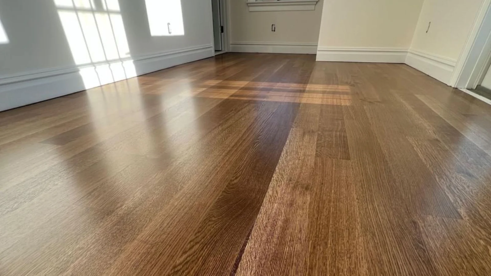 Mixed-width hardwood floor with warm brown tones and high-gloss finish in residential space